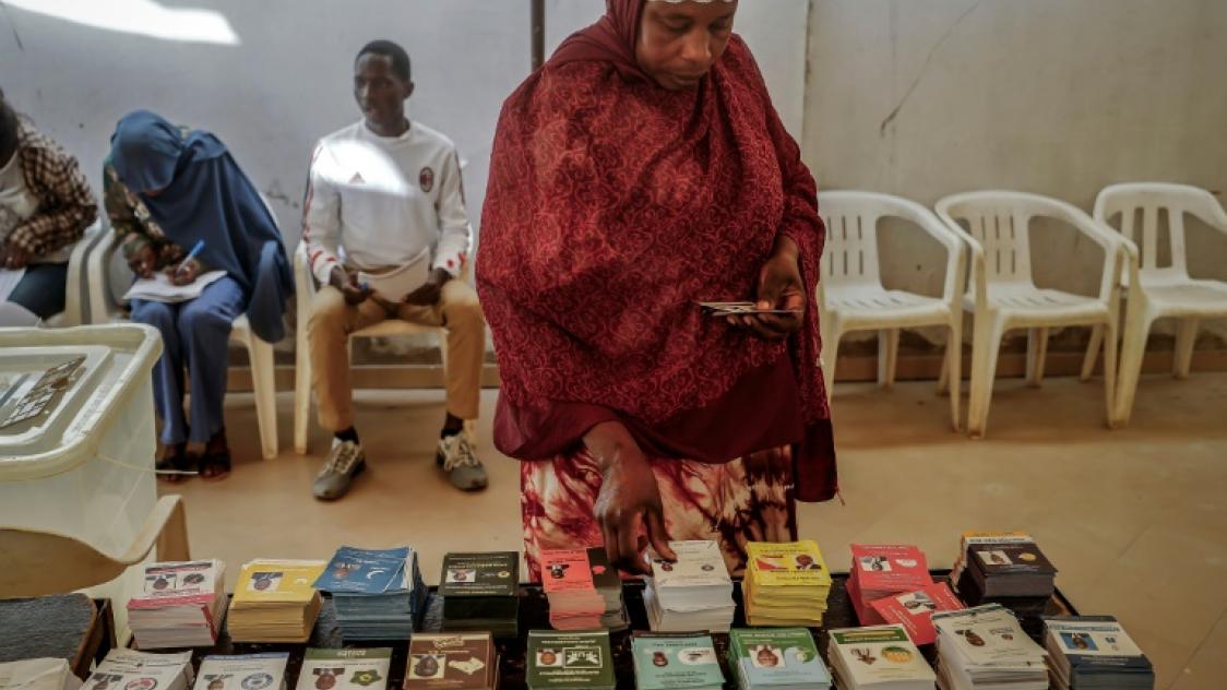 Une femme récupère un bulletin de vote dans un bureau à Dakar, le 24 mars 2024, lors des élections présidentielles