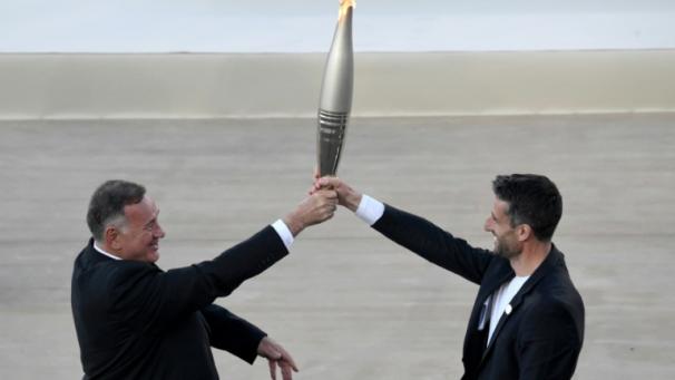 Le président du comité olympique hellénique Spyros Capralos (à gauche) remet la flamme olympique au président du Comité d