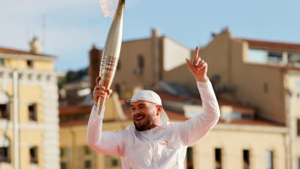 Le rappeur français Jul avec la torche olympique sur le Vieux Port, à Marseille, après avoir allumé le chaudron, le 8 mai 2024