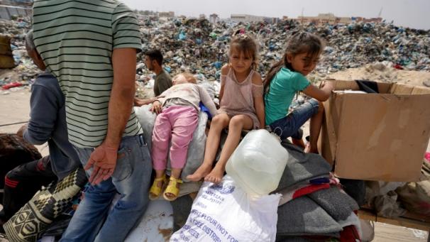 Des enfants palestiniens sont assis sur quelques affaires de la famille à leur arrivée à Khan Younès après leur fuite de Rafah  dans le sud de la bande de Gaza, le 28 mai 2024