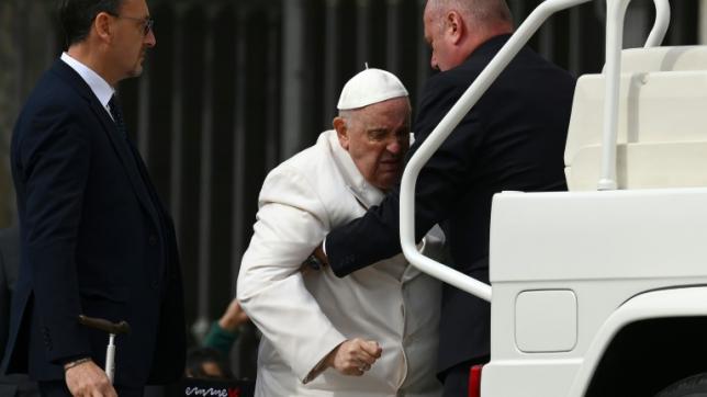 Le pape François est aidé pour monter dans sa papamobile à l