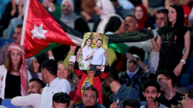 Un homme brandit une affiche du prince héritier Hussein ben Abdallah et de sa fiancée Rajwa al-Saif, lors d'un concert gratuit en l'honneur du couple royal au stade international d'Amman, le 29 mai 2023