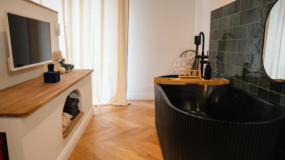 Dans la suite parentale, une baignoire &icirc;lot avec un carrelage en zelliges vert &eacute;meraude brillant, rehauss&eacute; de finitions dor&eacute;es.