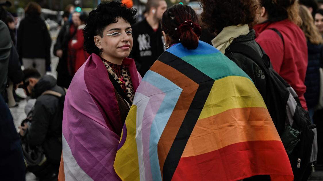 Supporters of the LGBTQ community wrapped in LGBTQ+ pride flags gather outside the Greek Parliament as lawmakers vote on a same-sex marriage and adoption for same-sex couples bill on February 15, 2024 in Athens. Greece