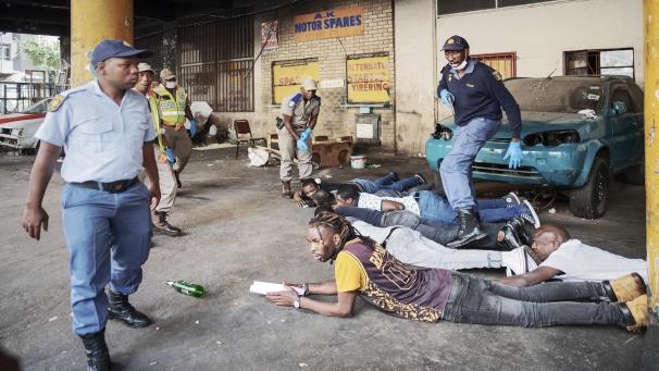 Des membres du service de police sud-africain (SAPS) arrêtent des suspects trouvés avec de l’alcool, qui va à l’encontre des règles nationales de confinement, à Hillbrow, Johannesburg.