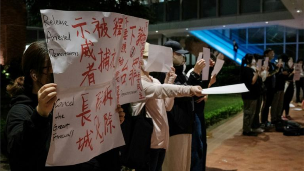 Des manifestants brandissent un panneau et des feuilles de papier blanc a l