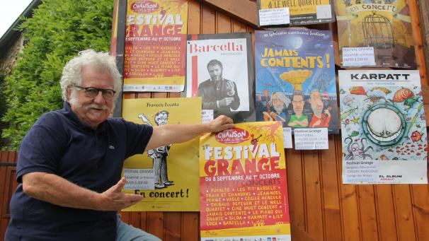 Jean-Pierre Beal devant les affiches et avec le programme 2023 du festival Grange.