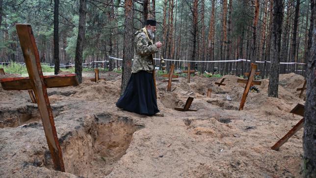 Un prêtre au milieu des tombes près d’Izioum, dans une forêt, le 23 septembre 2022.