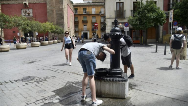 Des personnes se rafraichissent à une fontaine, le 13 juillet à Séville, dans le sud de l