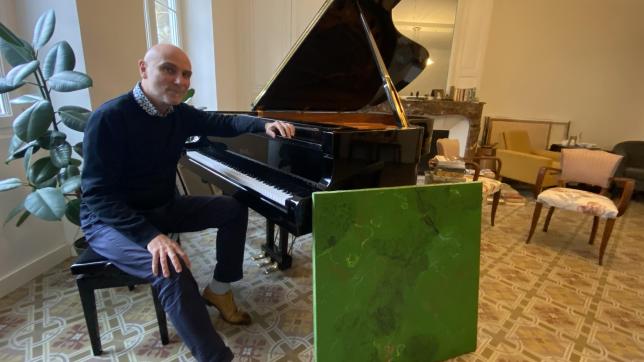 Le piano à queue est l’alter ego de Bertrand Bolognesi, qui montre une de ses peintures d’art abstrait. L’homme est aussi amateur de voyages.