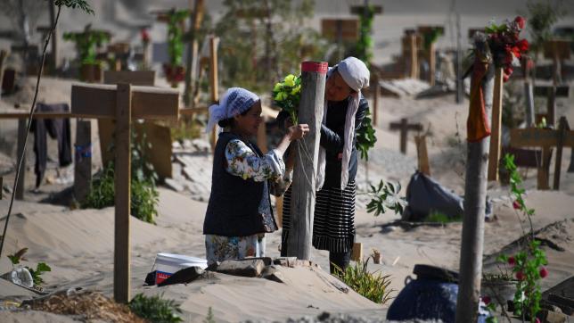 Deux femmes fleurissent une tombe dans un cimetière ouïghour, à Hotan dans le Xinjiang.